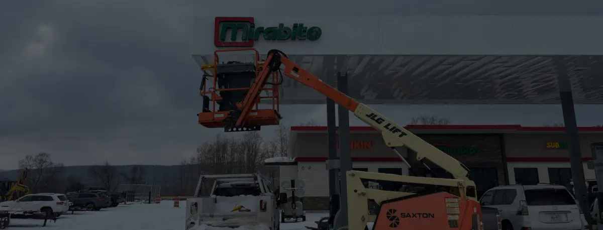 Installation of gas station canopy signage from a lift in winter