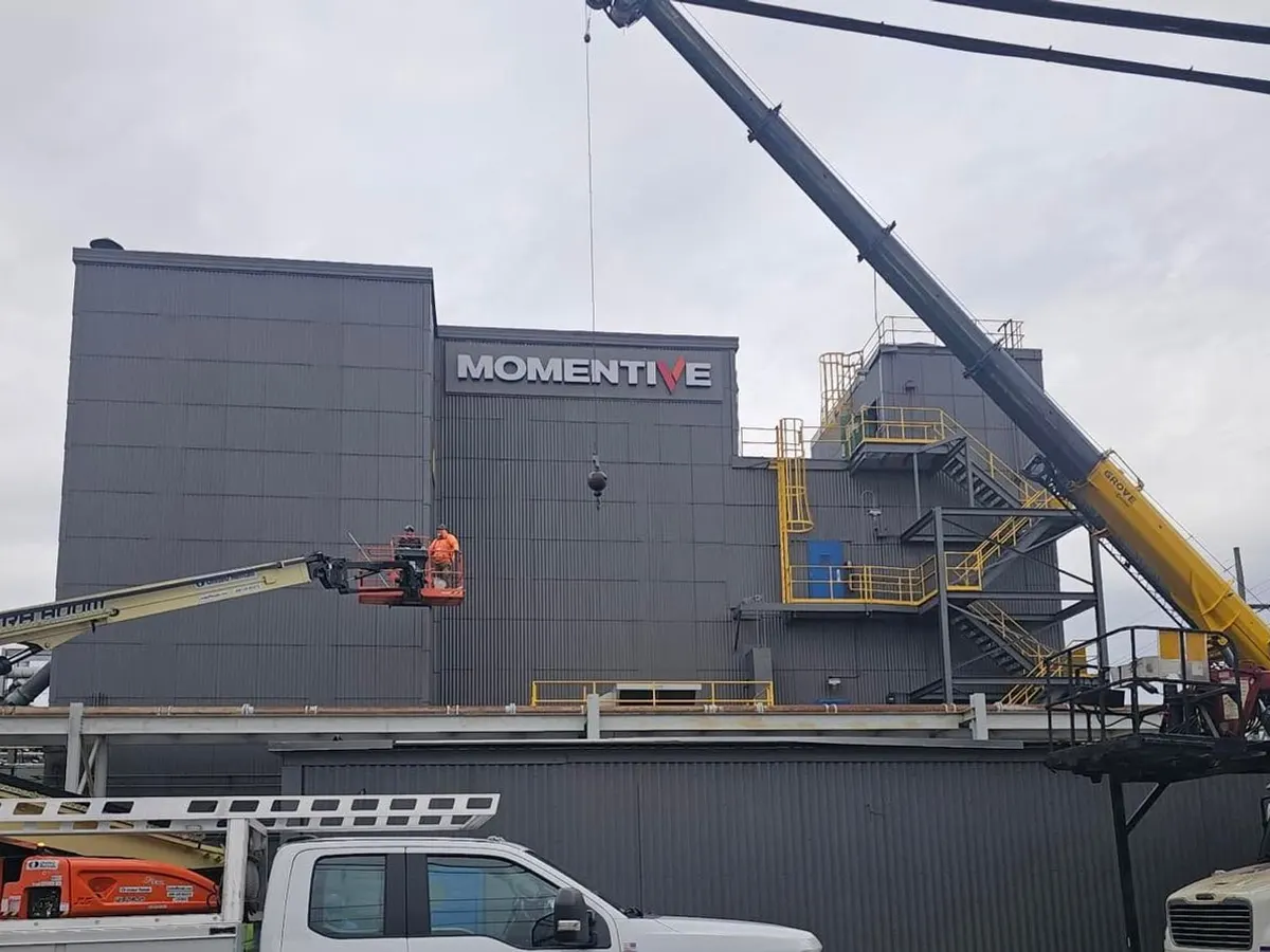 Saxton Signs crew installing Momentive channel letters on a new building with a crane